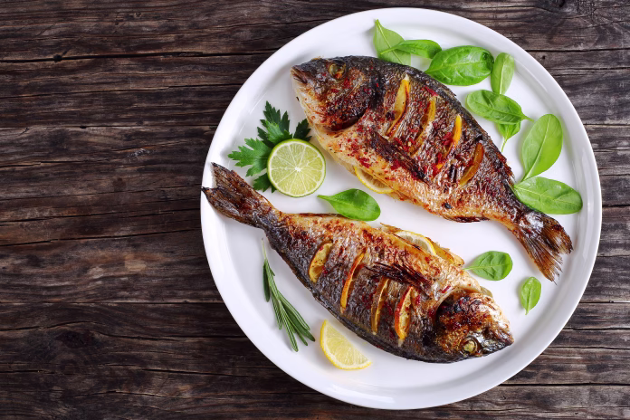 delicious-roasted-dorado-or-sea-bream-fish-with-lemon-and-orange-slices-spices-fresh-parsley-and-spinach-on-white-platter-on-old-dark-wooden-table-view-from-above-stockpack-istock delicious roasted dorado or sea bream fish with lemon and orange slices, spices, fresh parsley and spinach on white platter on old dark wooden table view from above