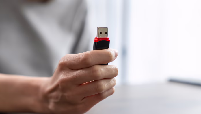 Hand holding usb flash drive with connecting to laptop at wooden table