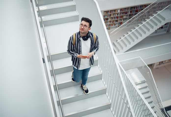 Library search, geek student or intelligent man for phd research, creative vision and knowledge in university. College, stairs above and person thinking of books for education, scholarship or study