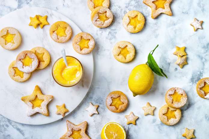 Linzer Christmas cookies filled with lemon curd and dusted with sugar on white marble board