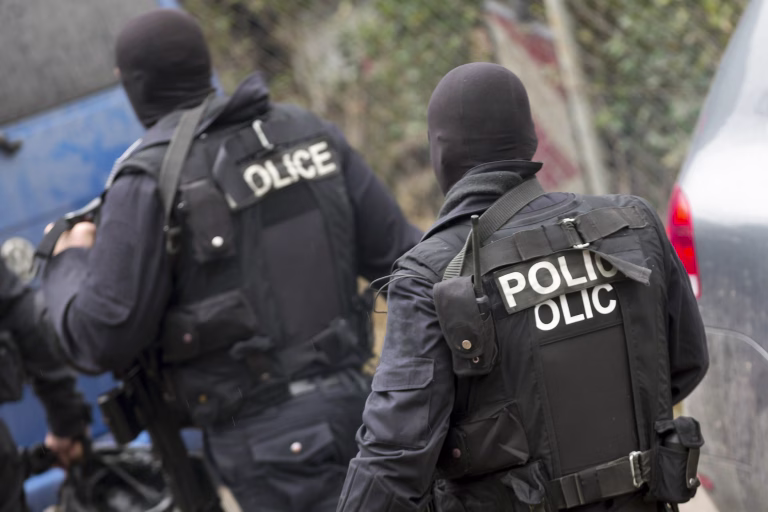 Special law enforcement unit. Special police force units in uniforms, bulletproof vests, firearms and guns. Masked police officers. Special Assault Team during mission. From their backs.
