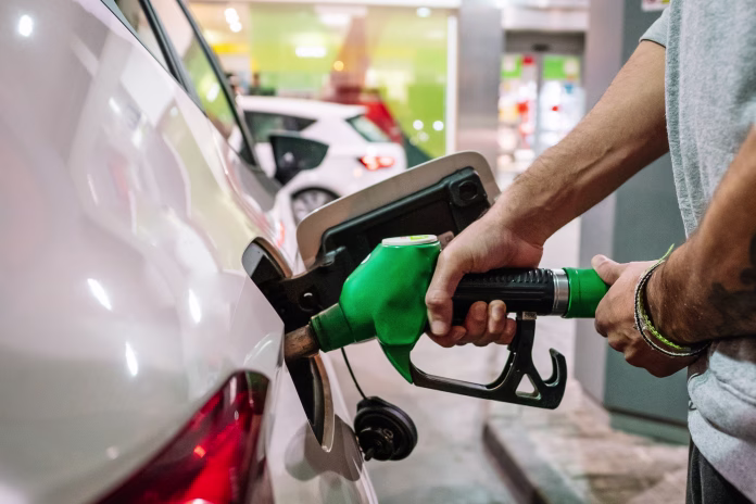 Unrecognizable male putting fuel dispenser in tank while refueling vehicle on self service gas station. High quality photo