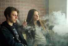 Dobra novica: večina mladih (še) ne posega po nikotinu Vape teenagers. Young cute girl in sunglasses and young handsome guy smoke an electronic cigarettes in the vape bar. Bad habit that is harmful to health. Vaping activity.