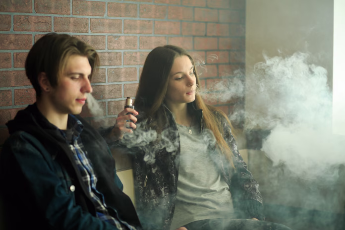 vape-teenagers-young-cute-girl-in-sunglasses-and-young-handsome-guy-smoke-an-electronic-cigarettes-in-the-vape-bar-bad-habit-that-is-harmful-to-health-vaping-activity-stockpack-istock Vape teenagers. Young cute girl in sunglasses and young handsome guy smoke an electronic cigarettes in the vape bar. Bad habit that is harmful to health. Vaping activity.