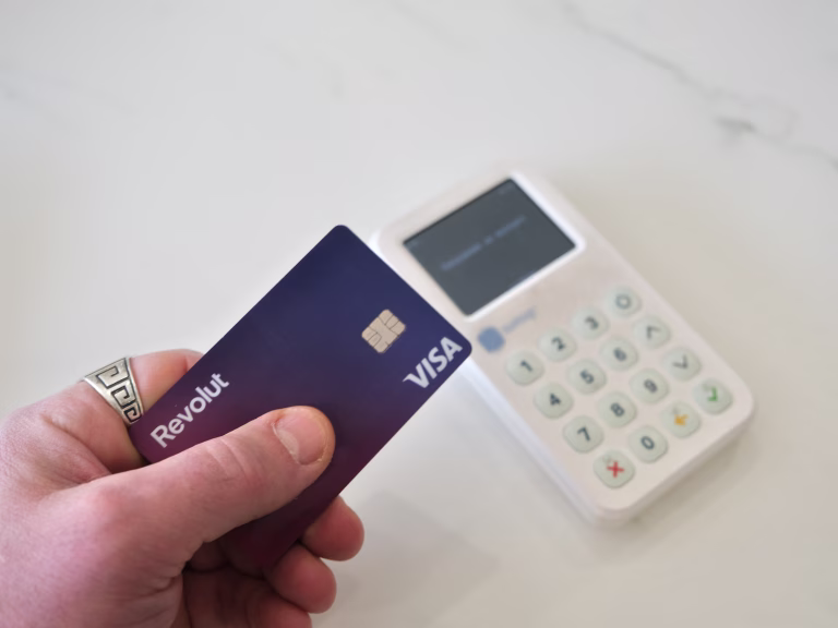 Wallers, France - 03 07 2025 : A hand holding a Revolut Visa card near a white payment terminal, illustrating a digital transaction in a modern, cashless world.