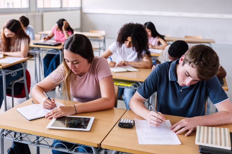 Young group of Gen Z students writing while learning during a class at high school. Education lifestyle concept.