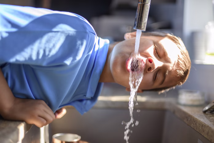 A Boy drinking water direct from the faucet