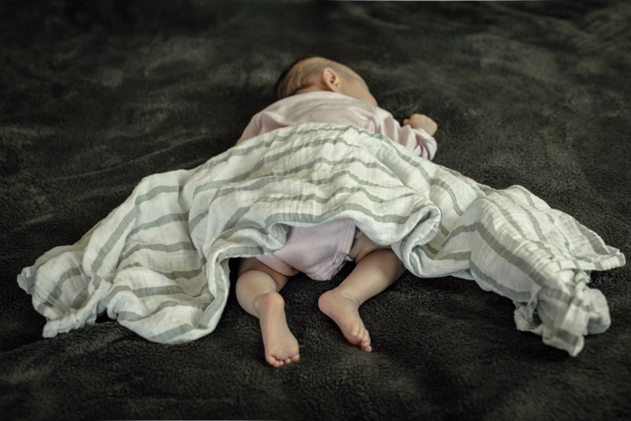a-newborn-baby-laying-on-her-stomach-and-with-loose-bedding-sids-awareness-stockpack-istock A newborn baby laying on her stomach and with loose bedding. SIDS awareness.