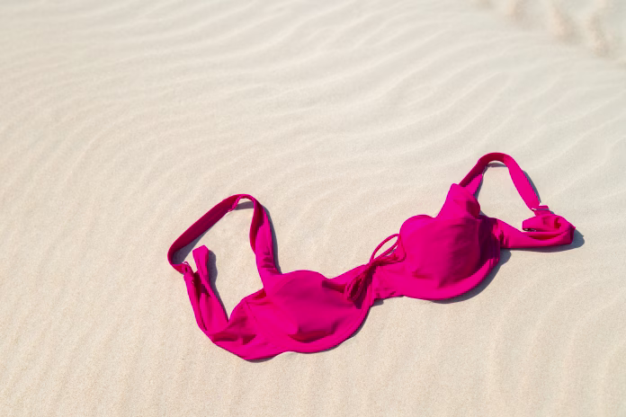 Close up of woman bra at nude beach. Concept of sunbathing naked on the sandy ocean beach. Naturalist lifestyle. Nobody.