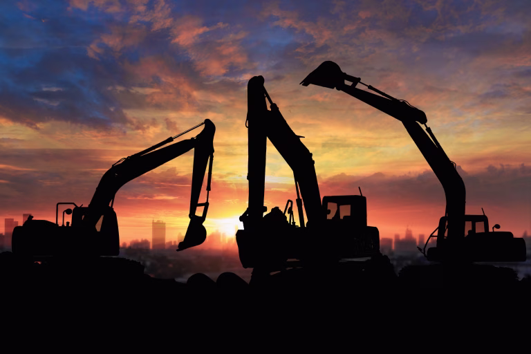 Crawler excavators silhouette are digging the soil in the construction site. on  sunset background