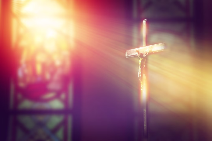 crucifix, jesus on the cross in church with ray of light from stained glass