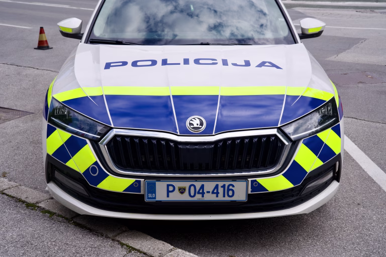 Front view of parked white, blue and yellow green Skoda police car at Slovenian City of Kranj on a sunny summer day. Photo taken August 10th, 2023, Kranj, Slovenia.