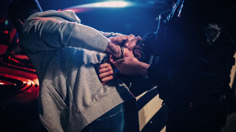 Male Policeman Forcing a Compliant Civilian on the Hood of Police Car. Officer Violently Pushing Man Against the Car and Handcuffing Him. Shocking Case of Police Brutality. Close up on Hands