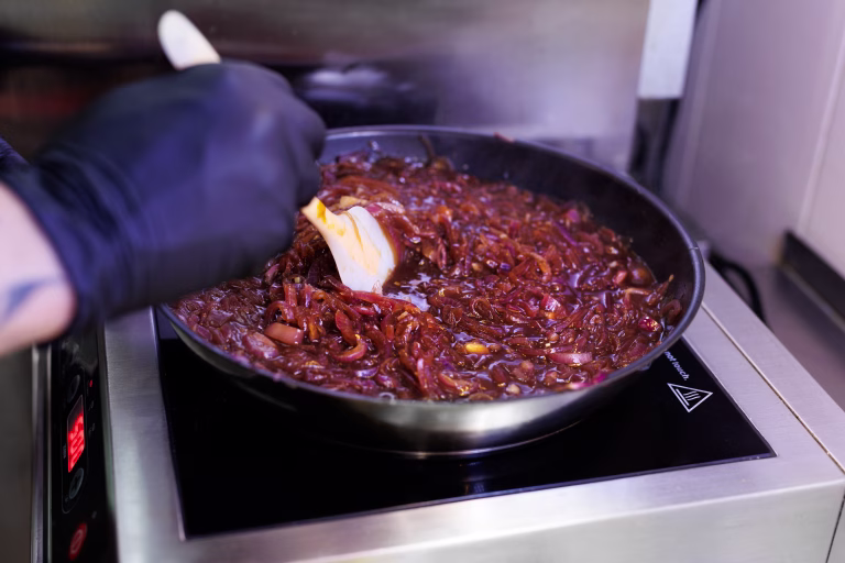 The chef prepares a sauce of caramelized onions in the restaurant kitchen