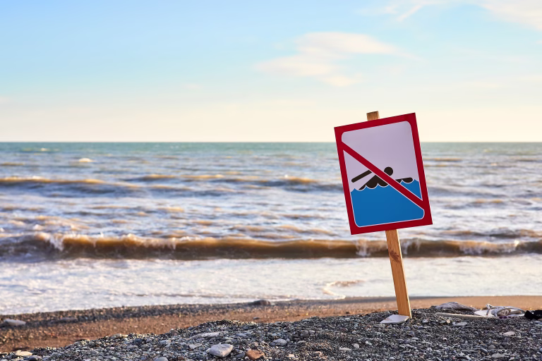 Warning no swimming sign with strong sea wave by the beach background
