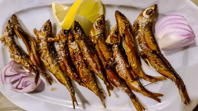 A plate full of grilled fresh bleak with lemon and onion served in a local restaurant in Virpazar, Lake Skadar National Park, Montenegro, Balkans, Europe. Local traditional food. Seasonal speciality