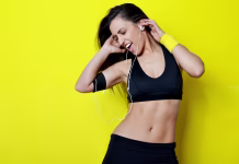 Kako izbrati glasbo za vadbo? beautiful fitness woman posing against the yellow background