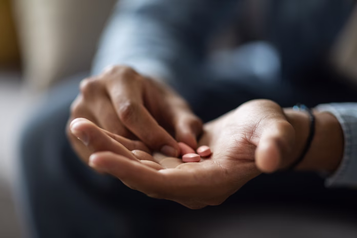closeup-shot-of-black-man-holding-few-pills-in-hand-while-sitting-on-couch-at-home-unrecognizable-african-american-male-taking-supplement-vitamin-or-painkillers-having-medical-treatment-cropped-stockpack-istock Closeup Shot Of Black Man Holding Few Pills In Hand While Sitting On Couch At Home, Unrecognizable African American Male Taking Supplement Vitamin Or Painkillers, Having Medical Treatment, Cropped