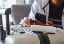 S kakšnim powerbankom ne smemo na letalo? Cropped image of a South Asian man waiting in airport lounge charging his phone using power bank before departure. Focus on the foreground.