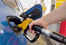 Cene goriv grejo v nebo: tako bi bilo, če država ne bi posegala v cene Man holds fuel nozzle into the gas tank of a car at the gas station