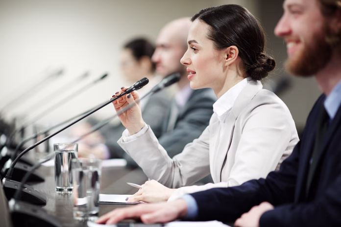 one-of-young-politicians-speaking-in-microphone-among-other-participants-of-conference-stockpack-istock One of young politicians speaking in microphone among other participants of conference