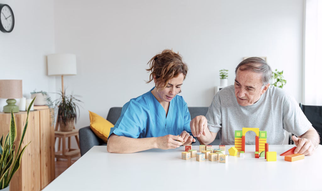 Professional nurse caregiver in geriatric clinic helps senior man with Alzheimer's disease - Old patient playing puzzle in retirement home - Healthcare and medical concept