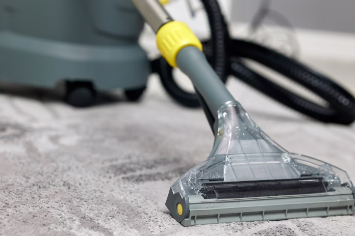 Professional wet and dry vacuum cleaner is standing on a gray carpet in a house, ready for perfect cleaning. Versatile cleaner is ideal for both wet spills and dry debris, ensuring a spotless home.
