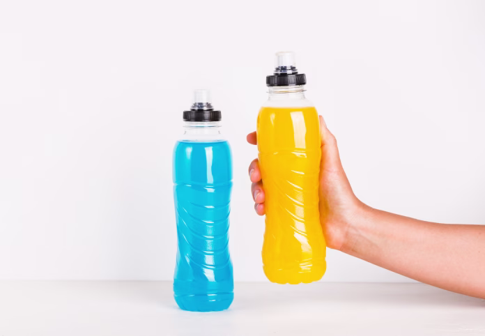 Sport isotonic drink in bottle, energy mineral hydration balance beverage copy space background. Woman hand holding sport mineral vitamin drink bottle.
