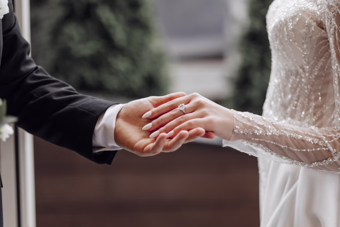 the-man-gently-holds-the-brides-hand-with-a-beautiful-golden-wedding-ring-enlarged-image-of-newlyweds-hands-wedding-concept-the-groom-gently-touches-the-bride-stockpack-istock The man gently holds the bride's hand with a beautiful golden wedding ring. Enlarged image of newlyweds' hands. Wedding concept. The groom gently touches the bride