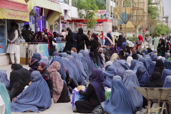 A number of poor Afghan women sitting in front of a bakery in capital Kabul to receive a piece of bread to feed their children.