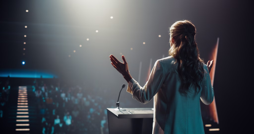 Caucasian Female Speaker with Expertise in Technology, Finance, Business, Politics, and Religion Coaching a Diverse Group of Young Specialists During a Presentation at a Strategic Growth Conference