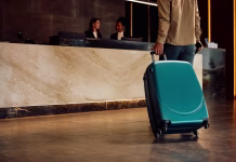 Ljubljana dobiva 500 novih hotelskih sob, cilja se na pet zvezdic Close up of hotel guest with a suitcase arriving reception desk. Copy space.