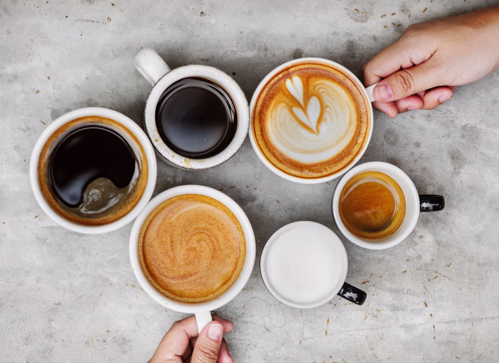 Directly Above Shot Of Hands Holding Coffee Cups On Table