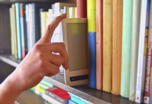 Kaj za bralce in založnike pomeni razvoj digitalnega založništva? Electronic book picked from a library shelf. The electronic book on a bookshelf among the many books in the library. Books and library concept.