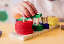 Vrtce za vse otroke, ne le za elito Kid playing with wood toys at pre school classroom. Kindergarten education smart games for children