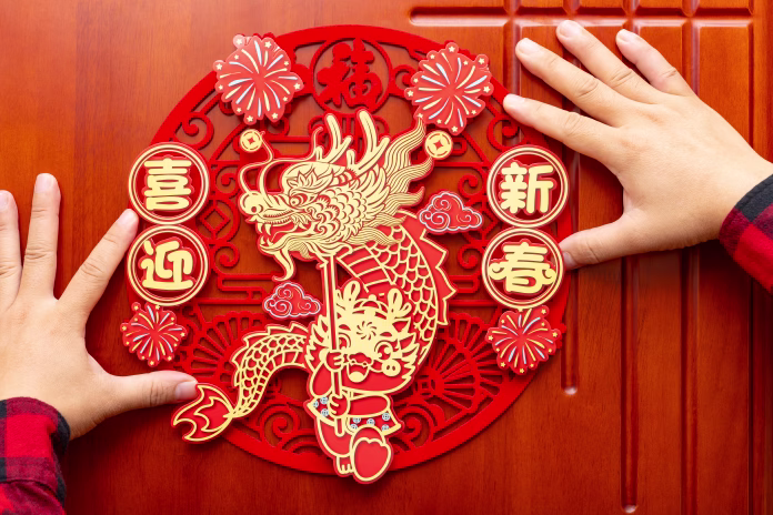 man sticking a Chinese New Year of the Dragon decoration to a door at horizontal composition translation of the Chinese words are fortune and welcome to the new year no logo no trademark