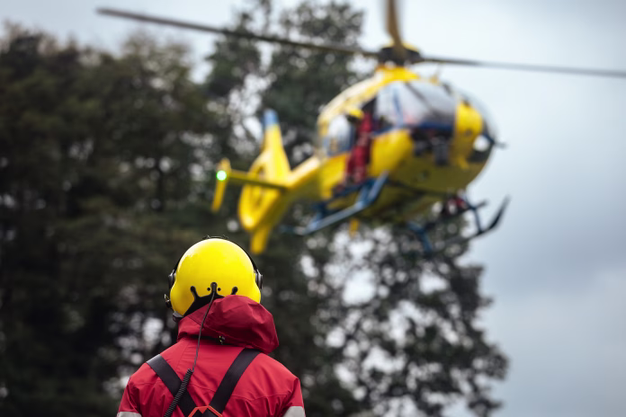 Rear view of paramedic against landing helicopter of emergency medical service. Themes rescue, help and hope.