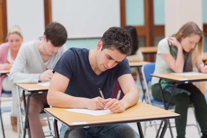 students-sitting-in-an-exam-hall-doing-an-exam-in-university-stockpack-istock Students sitting in an exam hall doing an exam in university