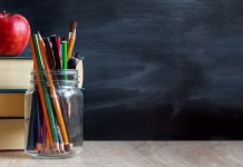 Kateri predmet bodo imele šole za nacionalno preverjanje znanja? The concept of education, stack of books, an apple, pencils against the background of the school blackboard