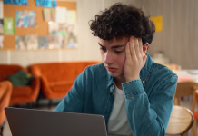 Kako mladi pri učenju na 5 načinov uporabljajo umetno inteligenco? Tired stressed headache overworked sad upset Caucasian male student guy pupil boy teen teenager studying laptop learning online education internet homework prepare to exams school college university. High quality 4k footage