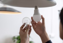 Ali LED žarnice motijo cirkadiani ritem? A young woman is changing a light bulb from an incandescent bulb to an LED bulb.