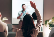 Pridobivanje mikrodokazil že v polnem teku – kaj točno že so mikrodokazila? Business people, seminar and convention with audience, question and interaction for feedback or engagement. Group, speaker and back of employee with hand raised for proposal or speech at presentation