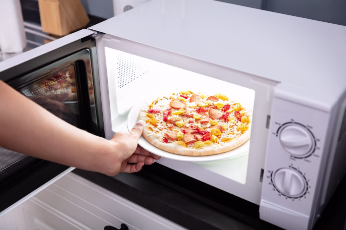 close-up-of-a-happy-woman-baking-pizza-in-microwave-oven-stockpack-istock Close-up Of A Happy Woman Baking Pizza In Microwave Oven