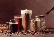 10 zanimivih dejstev o kavi! Coffee and chocolate drinks with scattered coffee beans on a brown background.