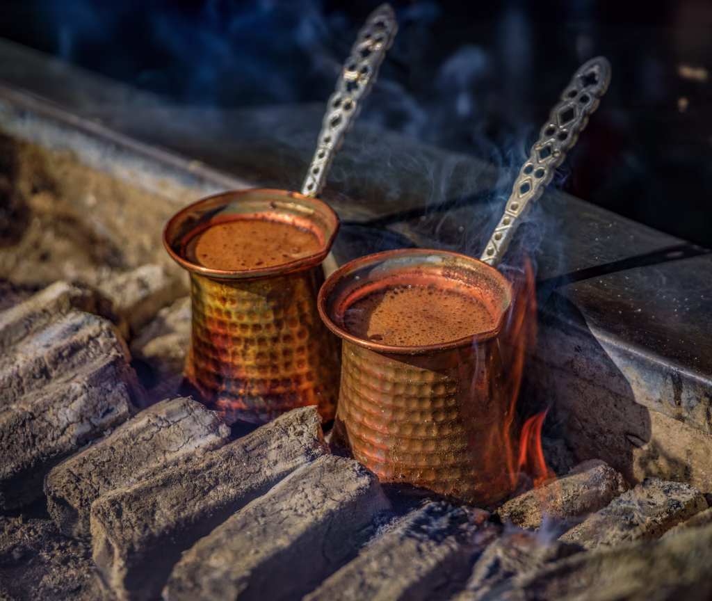 Cooking fresh aromatic traditional Turkish coffee on charcoal in cezve, original copper pots, authentic cuisine, Istanbul, Turkey