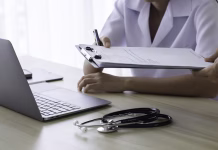 Če boste na bolniški, boste pod še strožjim nadzorom: Kaj prinašajo novosti? Doctor giving medical health report prescription and work on laptop computer at office desk in clinic or hospital.
