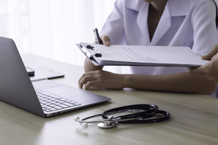Doctor giving medical health report prescription and work on laptop computer at office desk in clinic or hospital.
