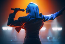 Zakaj ženske pop zvezdnice kritizirajo povprečne moške? Energetic Pop Artist Performing on Stage in Pink Feminine Clothes. Excited Audience Listening to the Tunes and Being Illuminated by a Vibrant Light Show. Footage from the Back