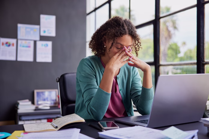 exhausted-businesswoman-feeling-stressed-holding-her-head-while-working-on-a-laptop-professional-african-american-woman-has-terrible-migraine-while-managing-tasks-in-office-with-copy-space-overwhelmed-stockpack-istock Exhausted businesswoman feeling stressed, holding her head while working on a laptop. Professional african american woman has terrible migraine while managing tasks in office with copy space. Overwhelmed businesswoman feeling tired and frustrated after read a bad news on financial market, overworked and burnout concept.