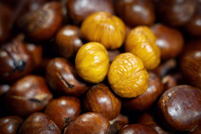 Freshly roasted chestnuts served hot at a street food stall, showcasing a traditional snack popular in local and outdoor markets.